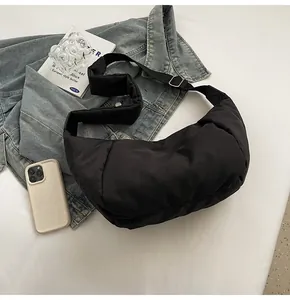 Détail du sac croissant en nylon noir souple avec boucle argentée et mise en scène flat lay