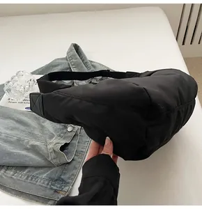 Détail du sac croissant matelassé noir avec bandoulière réglable et mise en scène lifestyle