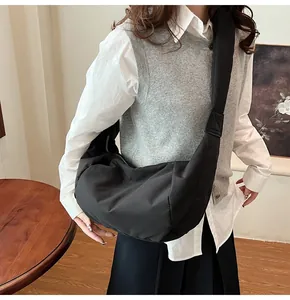 Sac bandoulière demi-lune noir en nylon avec bandoulière rembourrée porté par un mannequin