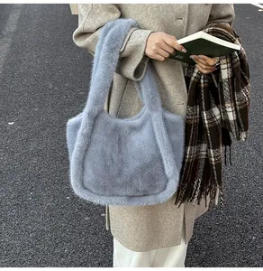 Blue plush tote bag carried by model wearing a beige coat and a scarf in winter