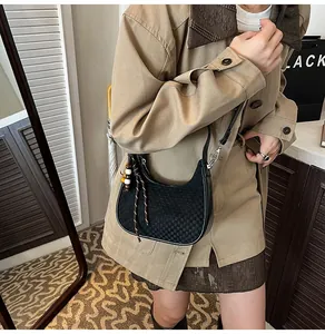 Detail of black checkerboard crescent bag with retro wooden bead charm on a beige coat