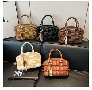 Detalle de cinco bolsos matelassé plisados en tonos vintage sobre un sofá de cuero
