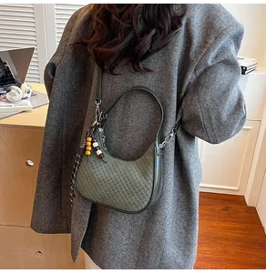 Detail of dark green hobo bag featuring woven texture and decorative checkered scarf