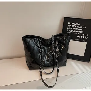 Detailed view of the black quilted tote bag with silver chain straps on marble