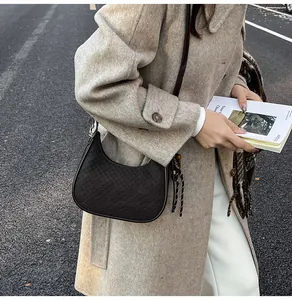 Detail of a dark brown hobo shoulder bag with checkered texture and tassel on a wool coat