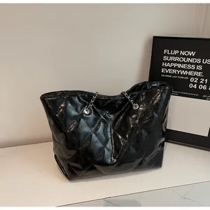 Detail of black quilted tote bag featuring glossy crackle leather and silver chain strap