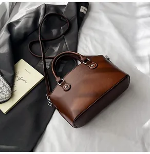 Detalle de bolso de mano marrón vintage con herrajes plateados y correa ajustable