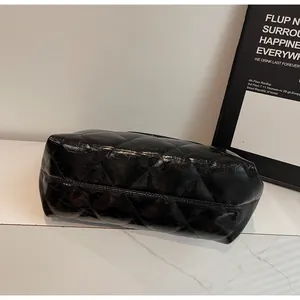 Detailed view of black quilted tote bag with shiny crinkle texture on marble surface