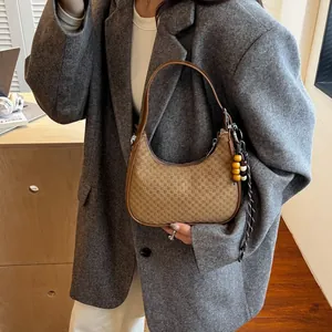 Brown checkerboard hobo bag with bead charm shown on a model in a grey blazer