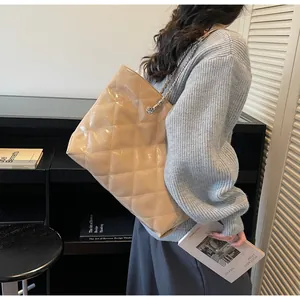 Detailed view of beige quilted tote bag with chain strap worn by a female model