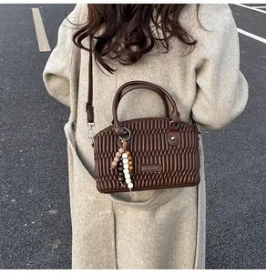 Detalle de bolso Boston marrón oscuro plisado con colgante de cuentas estilo bohemio