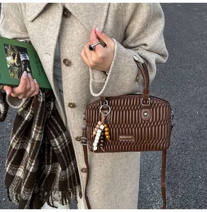 Detalle de bolso de cuero plisado marrón oscuro con cuentas de colores y anillo de plata