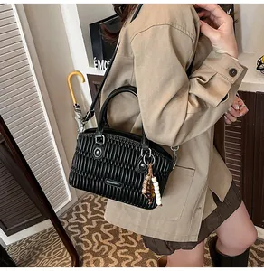 Detalle de bolso negro con textura plisada y colgante de cuentas de madera natural
