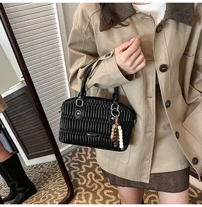 Detalle del bolso negro matelassé con colgante de cuentas usado por una modelo