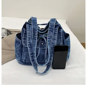 Detalle del bolso tote de mezclilla azul oscuro con bolsillo de hebilla y bolsillos laterales