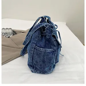 Primer plano detallado del bolso de mezclilla azul oscuro con cordón y textura lavada