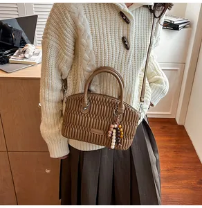 Detalle de un bolso Boston marrón acolchado con pliegues y cuentas de madera
