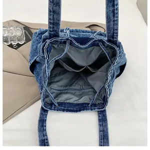Vista interior del bolso vaquero con forro, bolsillo con cremallera y cordón ajustable
