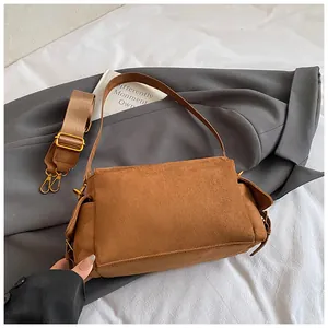 Detailed view of brown suede messenger bag with textured fabric and leather straps