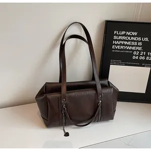 Détail du sac à main rétro marron foncé avec texture mate et pendentif coeur métallique