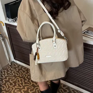 Bolso de mano acolchado blanco crema con colgante de cuentas lucido por una modelo