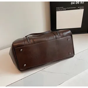 Vue détaillée du sac en cuir marron foncé montrant les quatre clous de protection en métal