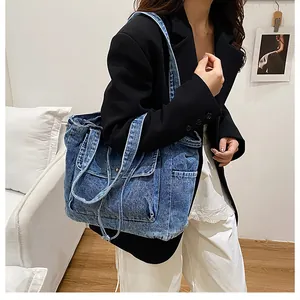 Vista detallada del bolso tote grande de mezclilla azul con lavado vintage y bolsillos en modelo