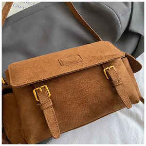 Detail of vintage brown suede messenger bag showing texture and golden metal buckles