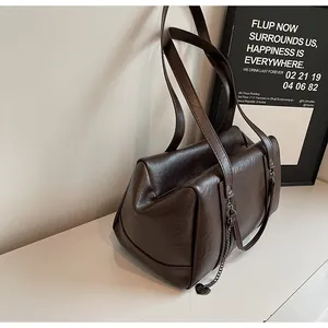 Détail du sac sous le bras marron vintage avec chaîne en métal et pendentif cœur
