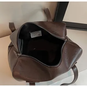 Close-up of a large brown Boston bag interior with zipper pocket and designer logo
