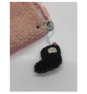 Détail du sac en peluche rose avec un pendentif chaussure fait main et étiquette
