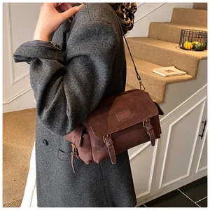 Close-up of vintage brown suede messenger bag with metal buckles and side pockets