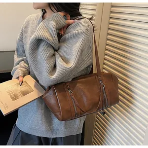 Vue détaillée du sac sous le bras marron foncé avec fermeture éclair et pendentif cœur