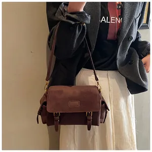 Detail of dark brown matte suede messenger bag with gold hardware and flap closure