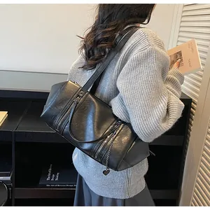 Détail d'un sac sous le bras en cuir noir texturé avec fermeture éclair et breloque