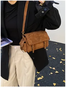 Close-up of vintage brown suede messenger bag with frosted texture and buckle detail