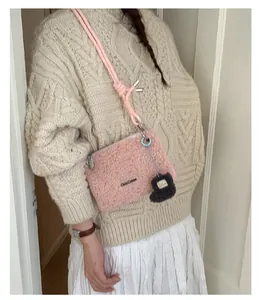 Détail du sac bandoulière en polaire rose avec sangle tressée et adorable pendentif ours
