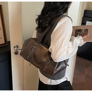 Détail du sac cabas en cuir marron avec fermetures éclair et pendentif en cœur