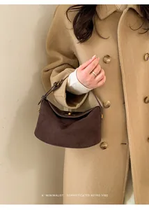 Détail du sac à main en daim marron foncé avec fermoir doré rétro et design minimaliste