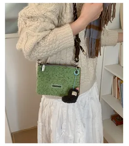 Détail du tissu polaire vert herbe avec pendentif en cœur et bandoulière en corde