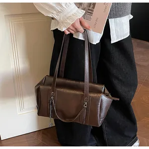 Détail du sac sous le bras vintage marron foncé avec finition polie et breloque chaîne