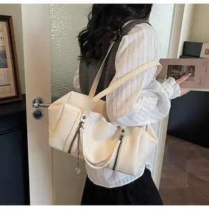 Détail du sac bandoulière blanc crème avec fermetures éclair et chaîne à pendentif cœur