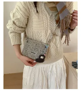 Détail du sac bandoulière gris en peluche avec étiquette et charm ours marron