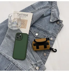 Detail of a mustard yellow canvas earphone pouch attached to a dark green leather phone case