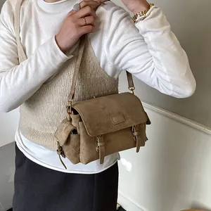 Brown faux suede messenger bag with gold buckles and adjustable shoulder strap worn by model