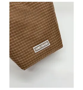 Detailansicht der braunen Karostruktur und des CHIC CRAZE Logos auf der Handtasche