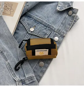Mini yellow canvas headphone pouch with hook detail on denim jacket background