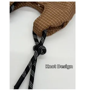 Nahaufnahme einer braunen Karo-Handtasche mit schwarz-weißem Schachbrett-Knotendesign