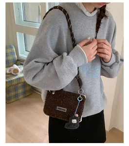 Détail du sac bandoulière en laine d'agneau avec sangle tressée et pendentif botte