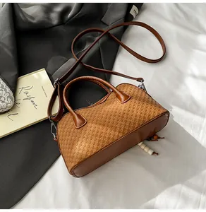 Detail of a brown woven pattern handbag with cylindrical handles and cream bead charm